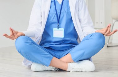 Kadın doktor klinikte yerde meditasyon yapıyor.
