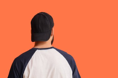 Turuncu arka planda şık şapkalı yakışıklı bir genç.