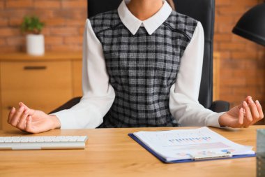 Genç iş kadını ofiste meditasyon yapıyor.