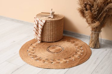 İçinde pampa otu ve hasır sepet olan vazo. Odada bej duvarın yanında.