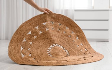 Kadın eli odada yere hasır halı seriyor.