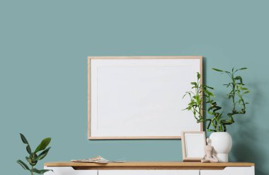 Oturma odasındaki nane duvarının yanındaki çekmecelerde yeşil dallı vazo ve fotoğraf çerçeveli.