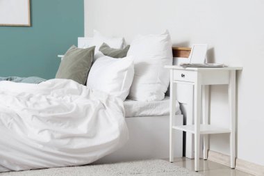 Yatak odasının içinde büyük, rahat bir yatak odası ve komodinin yanında, yakın plan.