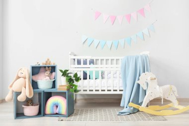 Bebek odasının içinde beşik, raf ve oyuncaklar var.