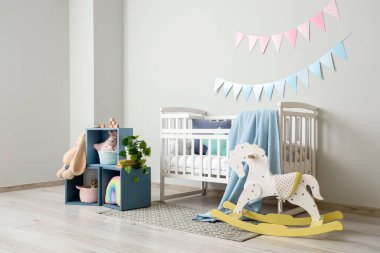 Bebek odasının içinde beşik, raf ve oyuncaklar var.