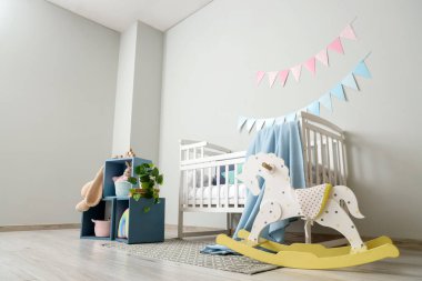 Bebek odasının içinde beşik, raf ve oyuncaklar var.