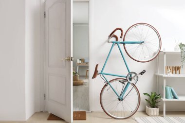 Koridorun iç tarafındaki açık kapının yanında modern bisiklet.