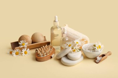 Bej arka planda papatya çiçekleri, spa taşları ve kozmetik ürünleri içeren kompozisyon, yakın plan