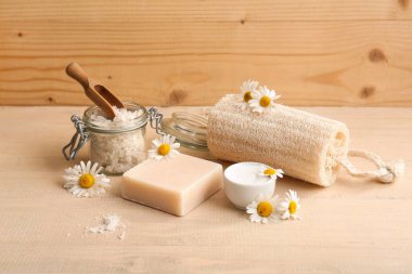 Sabun barı, papatya çiçekleri ve ahşap arka planda bir kavanoz deniz tuzu, yakın plan.