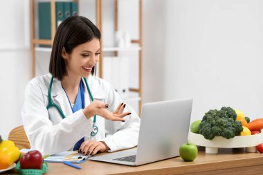 Ofisteki masada kadın beslenme uzmanı görüntülü sohbet.