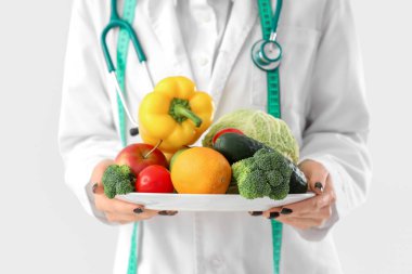 Beyaz arka planda sağlıklı yiyecekleri olan kadın beslenme uzmanı.