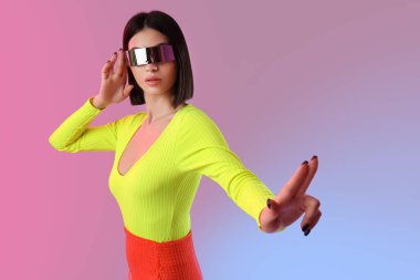 VR gözlüklü genç kadın arka planda sanal ekran kullanıyor