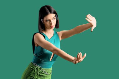 Yeşil arka planda VR gözlüğü kullanan çekici genç bir kadın.