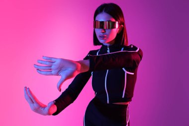 Pembe arka planda VR gözlüğü kullanan genç bir kadın.