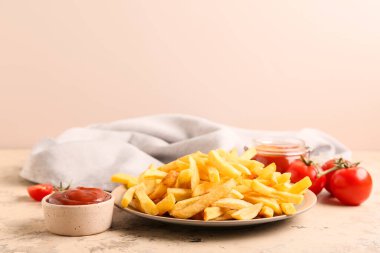Lezzetli patates kızartması ve bej arka planda ketçap tabağı.