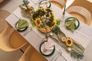 Tabaklar, mumlar ve güzel ayçiçekleri olan zarif bir masa.