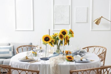 Hafif yemek odasında tabaklar, mumlar ve güzel ayçiçekleriyle servis edilen zarif bir masa.