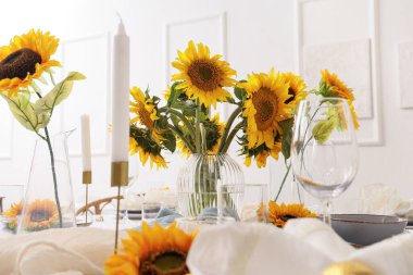 Bardaklar, mumlar ve güzel ayçiçekleri olan zarif bir masa, yakın plan.