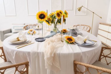 Tabakları, katlanmış peçeteleri ve güzel ayçiçekleri olan zarif bir masa.