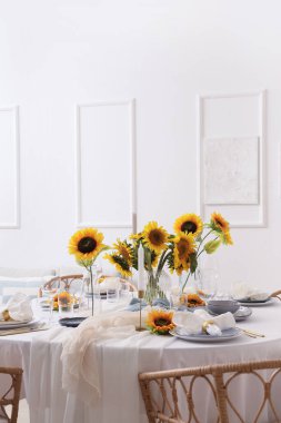 Tabakları, katlanmış peçeteleri ve güzel ayçiçekleri olan zarif bir masa.