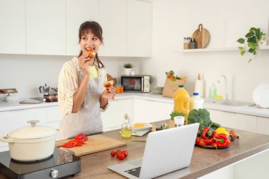 Genç bir kadın mutfakta kruvasan yiyor.