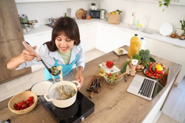 Genç kadın mutfakta çorba yapıyor.