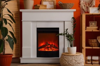 Katlanmış perdeli şömine, raf ünitesi ve oturma odasındaki turuncu duvarın yanındaki dekor.