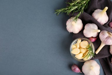 Taze sarımsak karanfilli cam kase ve gri arka planda biberiye.