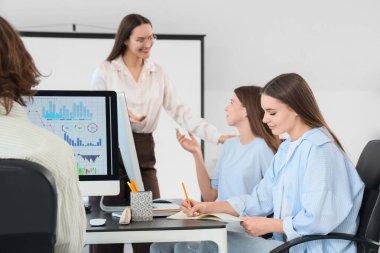 Öğretmeni olan genç öğrenciler bilgisayar laboratuvarında okuyor.