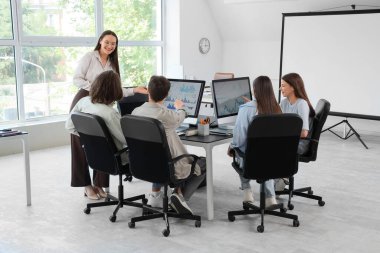 Öğretmeni olan genç öğrenciler bilgisayar laboratuvarında okuyor.