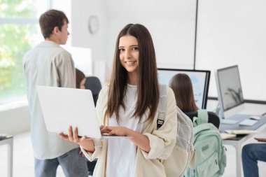 Okulun bilgisayar laboratuvarında dizüstü bilgisayarla çalışan kız öğrenci.