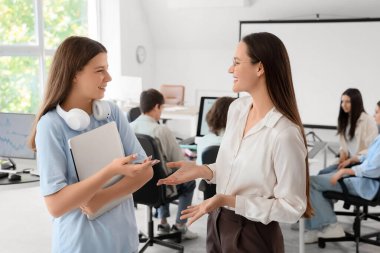 Bilgisayarlı kız öğrenci ve okulda bilgisayar öğretmeni.