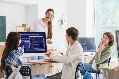 Okulun bilgisayar laboratuvarında öğrencilere ders veren bayan öğretmen.