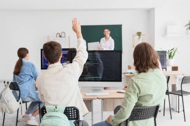 Okulun bilgisayar laboratuvarında öğretmenle birlikte okuyan bir grup genç öğrenci.