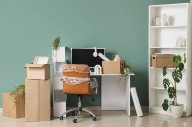 Taşındığı gün yeşil duvarın yanında kutuları ve raf ünitesi olan işyeri