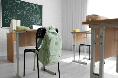 Sınıfta sandalyede asılı yeşil sırt çantası.