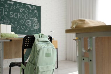 Sınıfta sandalyede asılı yeşil sırt çantası.