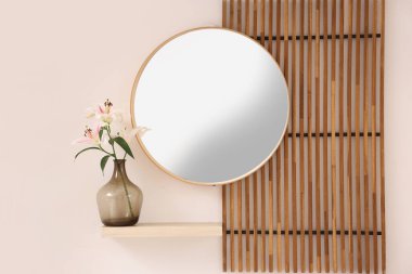 Beyaz duvarın yanındaki vazoda katlanan ekran, ayna ve nilüfer çiçekleri olan modern koridorun içi.