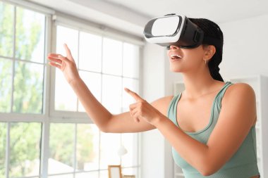 Evde VR gözlük kullanan Afro-Amerikalı bir kadın.