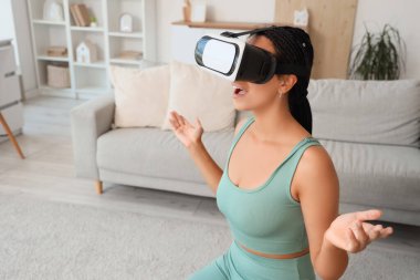 VR gözlüklü spor Afrikalı-Amerikalı kadın evde eğitim görüyor.