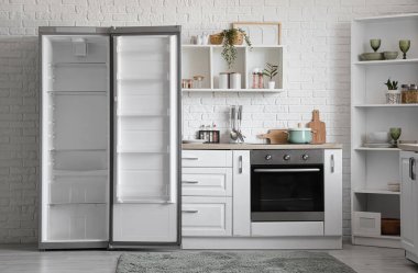 Boş buzdolabı, tezgah ve rafları olan mutfağın içi.