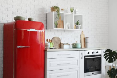 Kırmızı buzdolabı, tezgah ve raflı mutfağın içi.