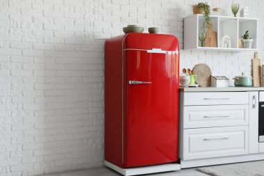 Kırmızı buzdolabı, tezgah ve raflı mutfağın içi.