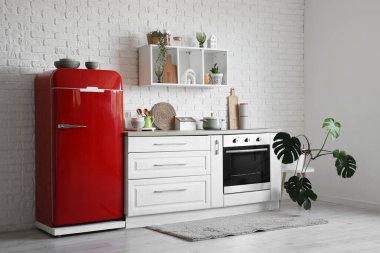 Kırmızı buzdolabı, tezgah ve raflı mutfağın içi.