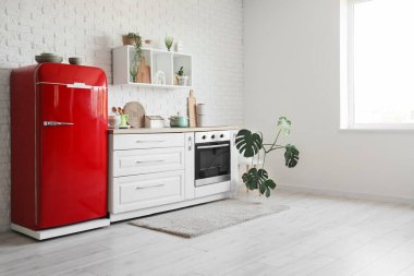 Kırmızı buzdolabı, tezgah ve raflı mutfağın içi.