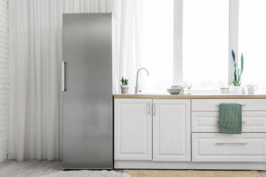 Modern buzdolabı, tezgah ve pencereli mutfağın içi.