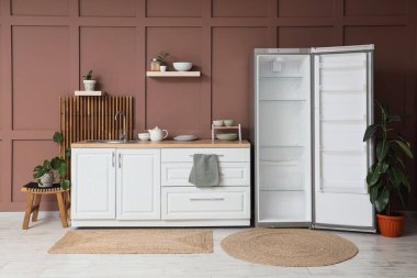 Boş buzdolabı, tezgah ve rafları olan şık bir mutfak.