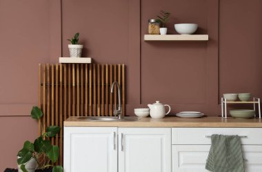 Mutfağın içinde tezgahlar, raflar ve bitkiler var.