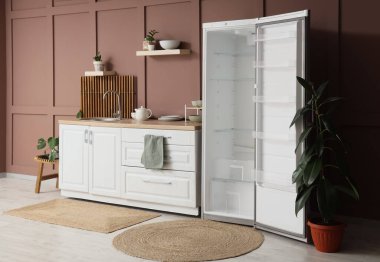 Boş buzdolabı, tezgah ve rafları olan şık bir mutfak.