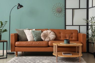 Kahverengi kanepesi, masası ve lambası olan şık bir oturma odası.